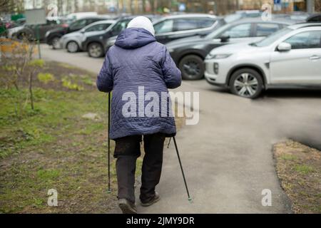 Donna con bastoncini da passeggio. Il pensionato è impegnato nella corsa a piedi. Cammina per la salute. La vecchia donna fa l'esercitazione fisica. Foto Stock