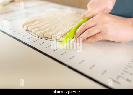 Vista laterale sul processo di cottura dall'impasto su un tappeto da forno con contrassegni sul tavolo da cucina, spazio copia Foto Stock