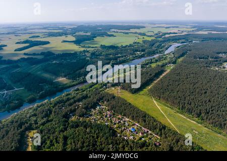 veduta panoramica aerea del villaggio verde con case nella foresta vicino ampio fiume Foto Stock