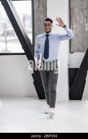 Felice uomo d'affari gesturing saluto camminare verso la macchina fotografica Foto Stock