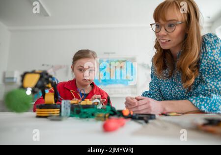 Giù sindrome scolgirl imparare circa la robotica dell'insegnante durante la classe a scuola, concetto di integrazione. Foto Stock