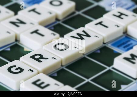 La parola di crescita fatta di pezzi scrabble blocca le lettere a bordo Foto Stock