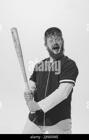 Appassionato giocatore di baseball maschile che indossa una divisa sportiva retrò e tiene la mazza isolata su sfondo bianco. Batteria da baseball d'epoca Foto Stock