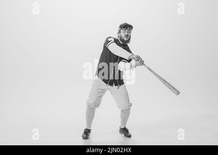 Ritratto monocromatico di giocatore di baseball maschile indossando una divisa sportiva retrò e tenendo la mazza isolata su sfondo bianco. Batteria da baseball d'epoca Foto Stock