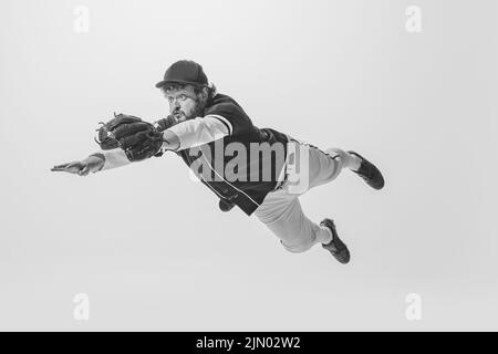 Ritratto monocromatico di giocatore di baseball maschile indossando una divisa sportiva retrò e tenendo la mazza isolata su sfondo bianco. Batteria da baseball d'epoca Foto Stock