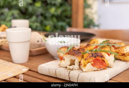 Focaccia all'italiana con pomodori ciliegini e rucola servita all'aperto con bicchieri di vino rosso. Pane secco tipico pugliese, fatto a Salen Foto Stock