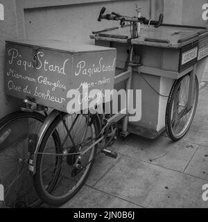 Una foto in scala di grigi di un carretto da bici d'epoca parcheggiato in strada Foto Stock