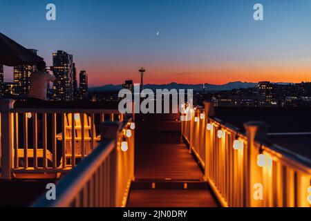Uomo che scatta foto al tramonto con lo skyline di Seattle dal ponte sul tetto di Capitol Hill Foto Stock