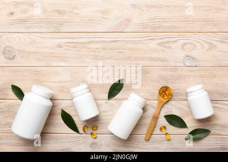 Le capsule di Omega-3 si trovano in un flacone bianco su un tavolo con il fondo verde delle foglie. Compresse di olio di pesce. Additivi biologicamente attivi omega 6, omega 9, vitam Foto Stock