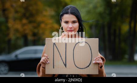 Primo piano protesta ragazza in piedi all'aperto guardando la macchina fotografica che tiene bandiera di cartone NESSUN membro della comunità contro la violenza domestica discriminazione razziale Foto Stock