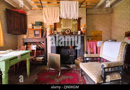 Una sala da pranzo, zona soggiorno con mobile da forno, camino di cottura e lavanderia appesa asciugando. In una ricreazione di una tipica casa di un lavoratore generico, casa da Foto Stock