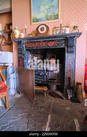 Il camino con stufa da cucina in ferro battuto e bollitore per tè con filtro antincendio. In una ricreazione di una tipica casa di un lavoratore generico, casa da 1955 a Bl Foto Stock