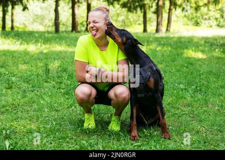 La ragazza con un doberman mostra l'amore l'un l'altro. Foto di alta qualità Foto Stock