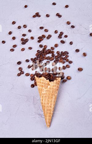 Cialda il cono gelato con i chicchi di caffè. Dessert verticale per bevande su sfondo bianco. Foto Stock