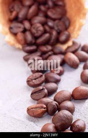 Primo piano verticale dei chicchi di caffè. Cialda il cono gelato con i grani versati. Foto Stock