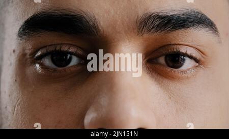 Extreme viso primo piano giovane ispanico maschio occhi uomo arabo con le sopracciglia marroni che lampeggiano guardando la macchina fotografica dimostrare la vista perfetta dopo Foto Stock