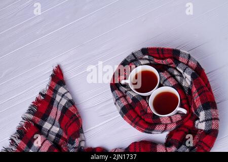 Vista dall'alto Coppia di tazze di tè avvolte in sciarpa. Sfondo bianco della scrivania con spazio per le copie. Foto Stock