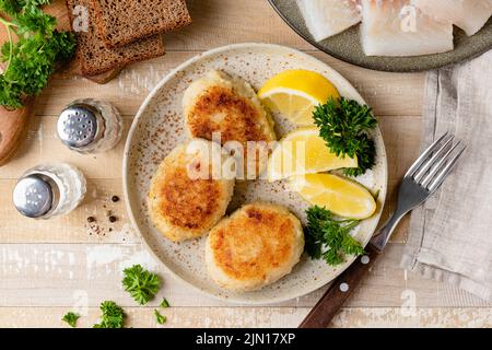 Torte di pesce, polpettine o cotolette su un piatto. Tortino di merluzzo fritto in pangrattato Foto Stock