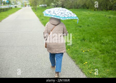 Donna con ombrello in estate. La ragazza cammina attraverso il parco con l'ombrello dalla pioggia. Passeggia per la città. Foto Stock