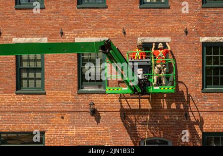 Lavoratori edili che installano nuove finestre su un edificio mulino nel centro di Bideford Maine Foto Stock