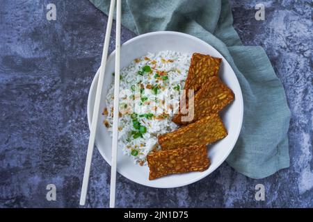 Tempeh fritto con riso in una ciotola, cibo vegetariano Foto Stock