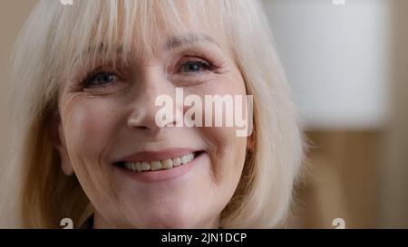 Donna anziana pensiva pensiva pensante finestra pensante malinconico calma relax divano a casa guardare la macchina fotografica sorridente bella donna adulta Foto Stock