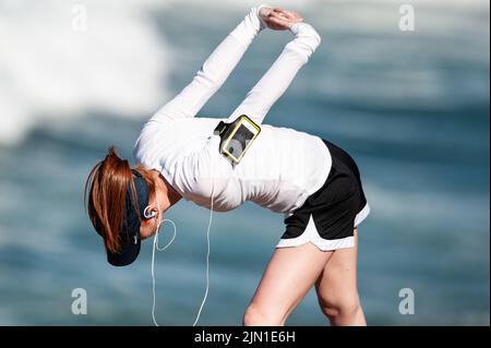 Immagine di una donna che si allunga prima della sua corsa mattutina sulla spiaggia. Secondo riscaldamento, Beach Runner, San Francisco, California, salute, Benessere, esercizio fisico Foto Stock