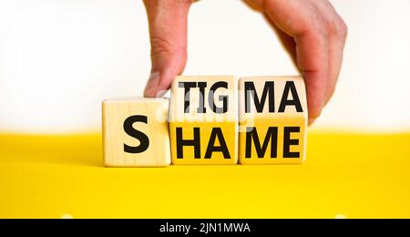 Stigma o simbolo di vergogna. Concetto parole stigma o vergogna su cubi di legno. Mano dell'uomo d'affari. Bella tabella gialla sfondo bianco. Business stigma o s Foto Stock