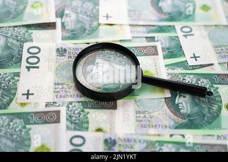 Sfondo dal denaro. Banconote polacche e lente di ingrandimento. 100 contanti zloty Foto Stock