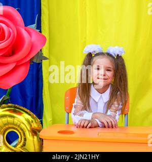 Lysychansk, Ucraina. 1 settembre 2021 - una ragazza con due code di ponytail, archi bianchi e una blusa bianca guarda la macchina fotografica e sorride durante il Foto Stock