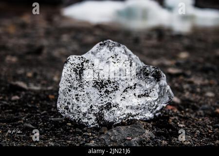 Una piccola pietra bianca e nera macchiata sul terreno circondata da una strada bagnata, primo piano Foto Stock