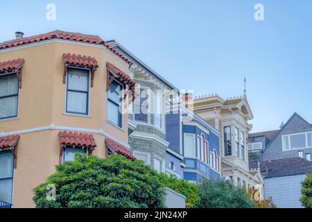 Fila di case in un angolo basso vista a San Francisco, California. Case Italianate, tradizionali e vittoriane in fila contro il cielo chiaro backgroun Foto Stock