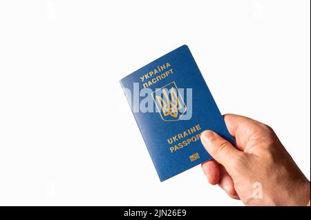 Passaporto ucraino biometrico in una mano femminile su sfondo bianco. Minimalismo. Identificazione, viaggi nel mondo, emigrazione, affari, turismo. Foto Stock