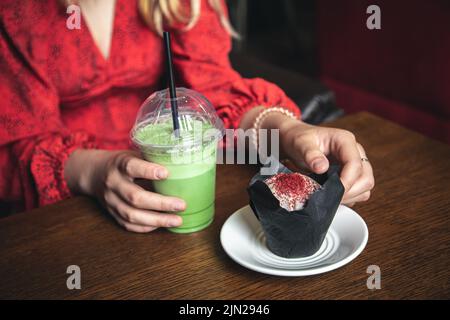 Primo piano torta di ghiaccio e cupcake in un caffè in mani femminili. Foto Stock