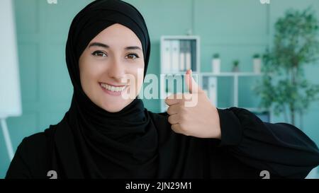 Primo piano ritratto femminile in ufficio musulmano felice soddisfatto soddisfatto islamo arabo donna indossando nero hijab guardando la macchina fotografica sorridente toothy ragazza Foto Stock