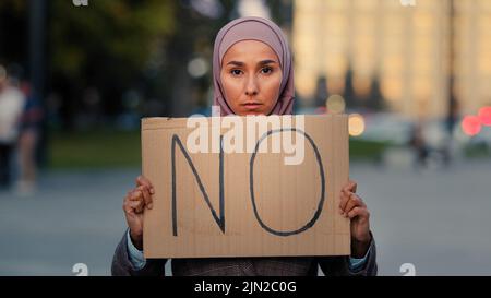 Stop al razzismo Nessun concetto immigrato arabo donna musulmana in hijab proteste contro discriminazione la vaccinazione vax in piedi in città. Ragazza islamica in attesa Foto Stock