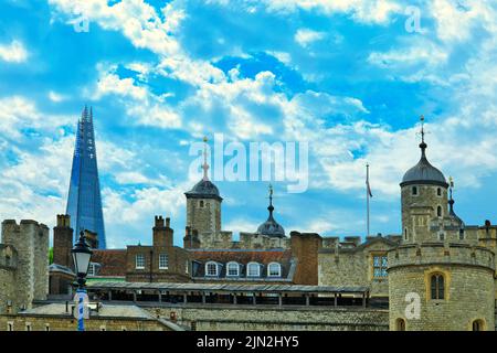 Torre di Londra sulla riva nord del Tamigi con il grattacielo Shard che si innalza dietro di essa in lontananza dall'altro lato del fiume Foto Stock