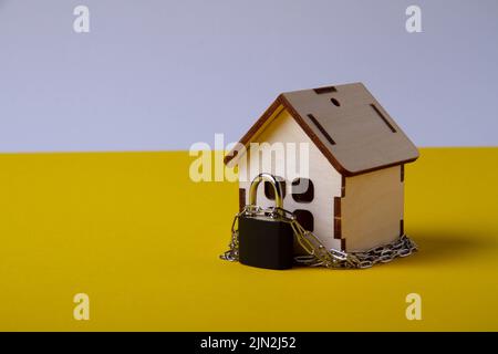 Arresto dell'alloggiamento. Casa del castello. Piccola casa giocattolo e una catena con un lucchetto. Sfratto per mancato pagamento. La porta chiusa a chiave della casa. Foto Stock