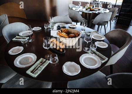 Evento splendidamente organizzato - tavolo rotondo servito banchetto pronto per gli ospiti, tavolo rotondo decorato con piatto vuoto, bicchieri, forchette, tovagliolo. Elegante tavolo da pranzo Foto Stock