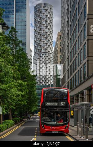 Londra, Regno Unito - Giugno 10 2022: Autobus rosso a due piani in attesa di una stazione degli autobus a Canary Wharf, con grattacieli futuristici sullo sfondo Foto Stock