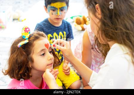 BAKU, AZERBAIJAN- 13 MAGGIO 2019 : ragazza disegna il trucco della bambina dell'acqua. Pittura del viso. Divertimento per bambini. Foto Stock