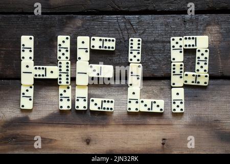 La parola help è posta da lettere domino su un vecchio tavolo di legno primo piano Foto Stock