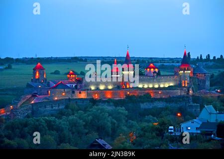 Castello di Kamianets-Podilskyi con illuminazione notturna con torre rossa illuminata da proiettore a Kamyanets-Podilski, Ucraina. L'Europa viaggia diversità. Foto Stock