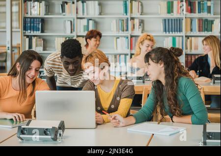 Studenti diversi che parlano dei dati sul notebook Foto Stock