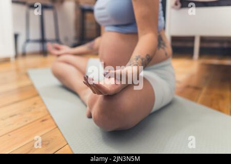 donna incinta meditante a casa. Foto di alta qualità Foto Stock