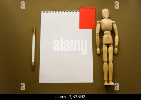 Bambola di legno e un pezzo di carta. Manichino in legno con fogli di carta concept, spazio vuoto. Creatività e arte Foto Stock