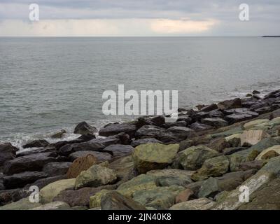 Spiaggia rocciosa. La riva è fortificata con enormi pietre. Onde grandi sul molo. Viaggio in Turchia. Grande onda. Tempo ventoso Foto Stock