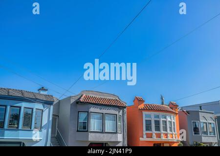 Facciata di piccole case adiacenti con scale all'entrata sul lato di San Francisco, California. Esterno colorato di case con filo elettrico Foto Stock