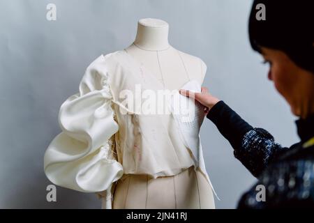 Donna dressmaker che prova sul manichino i suoi vestiti disegnati. Foto Stock