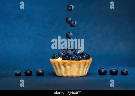 Design surreale con mirtillo galleggiante. Crostata di mirtillo. Concetto creativo di fly food. Bacche di levitazione Foto Stock